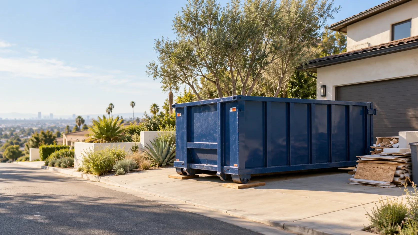 Deep navy roll-off dumpster placed on a Los Angeles driveway